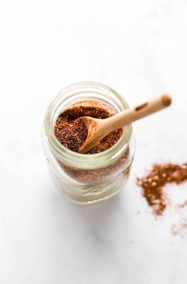 Taco seasoning in a small spice jar. A wooden spoon is resting in the jar.