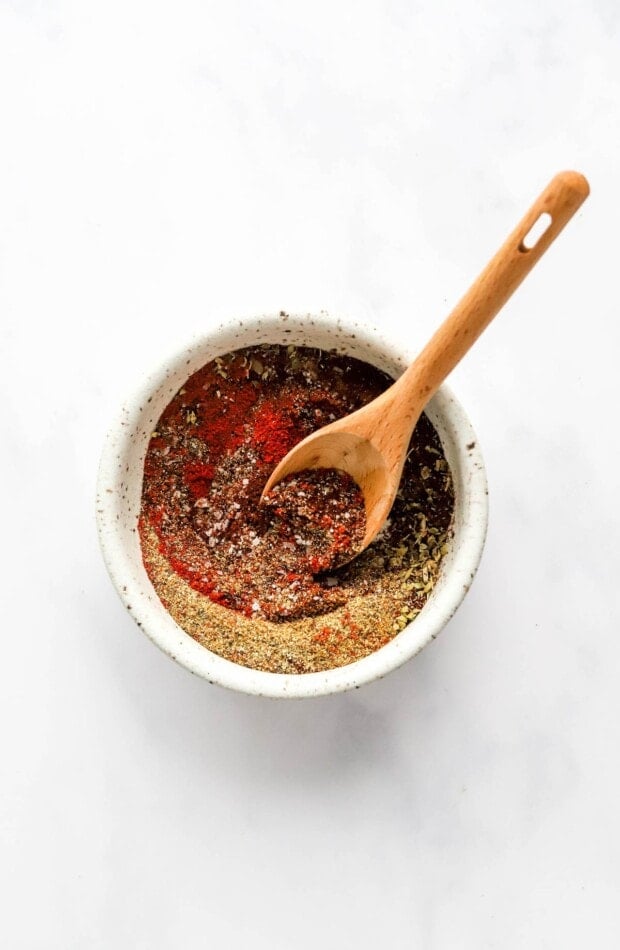 Spices mixed together with a wooden spoon in a small bowl.