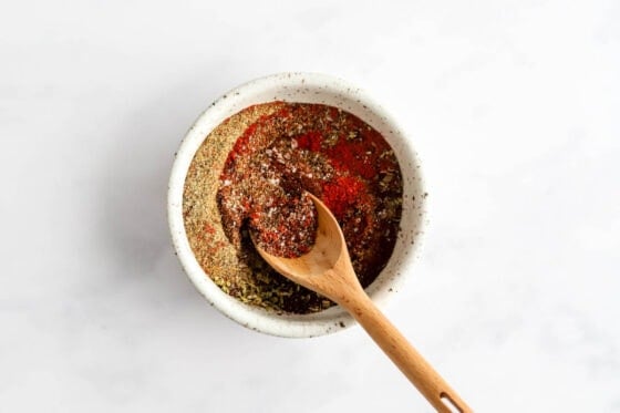 Spices mixed together with a wooden spoon in a small bowl.