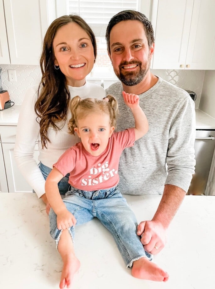 Baby announcement with a couple with toddler girl in a big sister shirt.