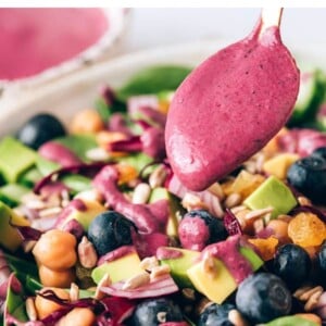 Drizzling blueberry tahini dressing on a spinach blueberry salad.