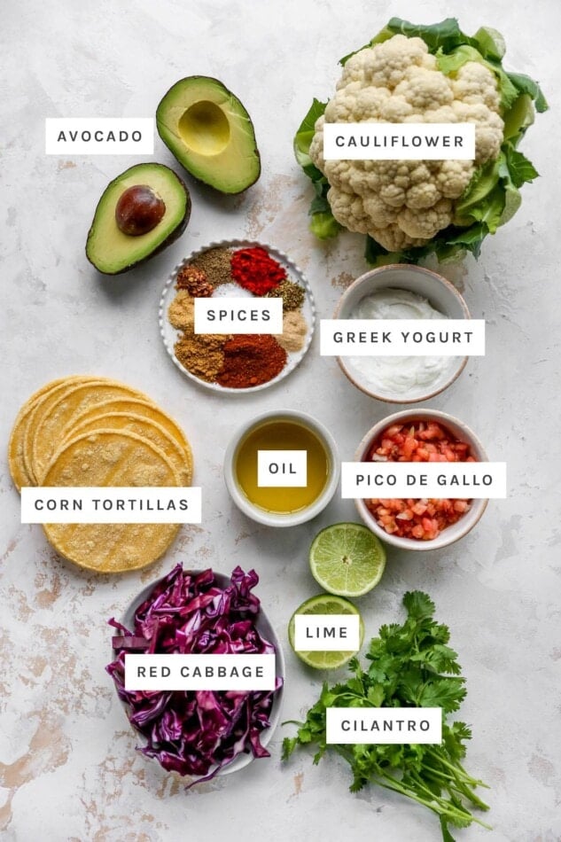 Ingredients measured out to make cauliflower tacos: avocado, cauliflower, spices, Greek yogurt, oil, corn tortillas, pico de gallo, lime, red cabbage and cilantro.
