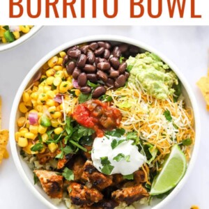 A chicken burrito bowl with corn salad, black beans, guacamole, shredded cheese, lime slices, greek yogurt and salsa served over cilantro lime rice.