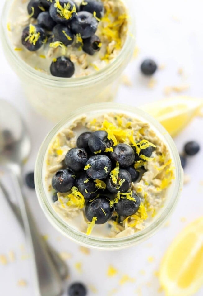 Overhead view of overnight oats in a mason jar topped with blueberries and lemon zest.