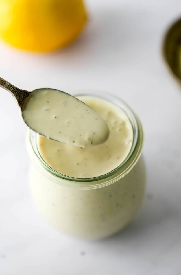 A tulip jar containing healthy caesar salad. A spoonful is being lifted out of the top of the jar.