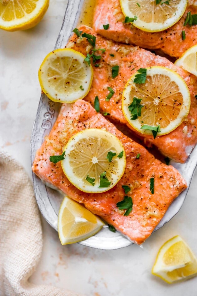 Salmon filets on a plate garnished with lemon slices and parsley.