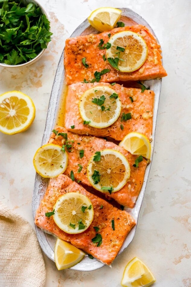 Honey Lemon Garlic salmon filets on a plate garnished with lemon slices and parsley.