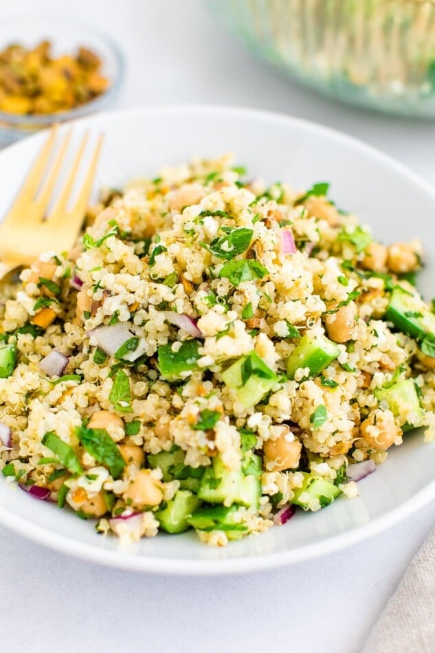 Quinoa salad on a white plate with a fold fork.