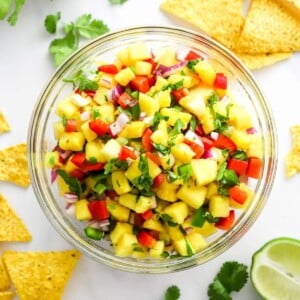 Pineapple salsa in a serving bowl with chips scattered around.