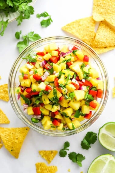 Pineapple salsa in a serving bowl with chips scattered around.