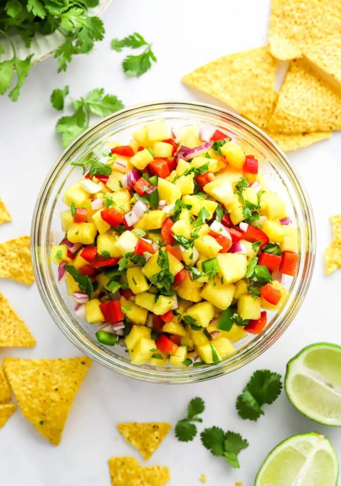 Pineapple salsa in a serving bowl with chips scattered around.