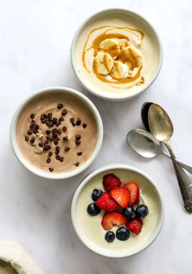 Three small dishes containing protein pudding 3 ways: peanut butter, chocolate, and vanilla.