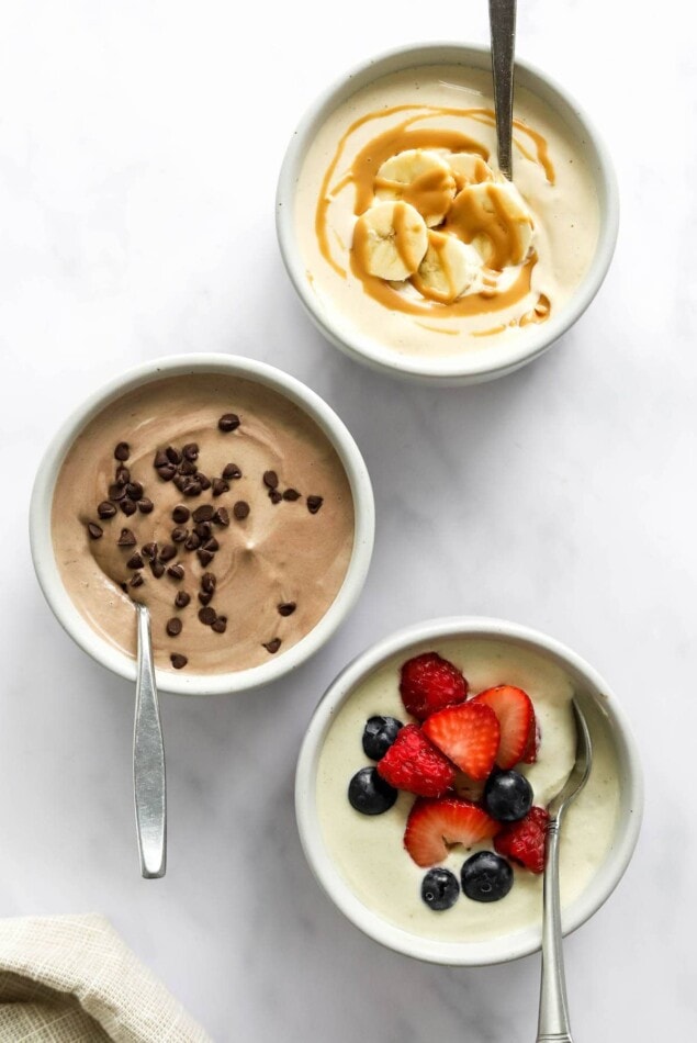 Three small dishes containing protein pudding: peanut butter, chocolate and vanilla.