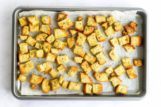 Sourdough croutons on a baking sheet lined with parchment paper.