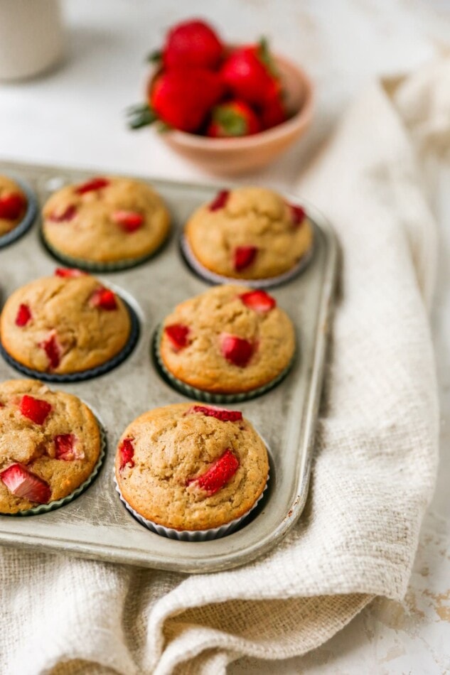 Strawberry yogurt muffins wrapped in silicone liners resting in a muffin tin.