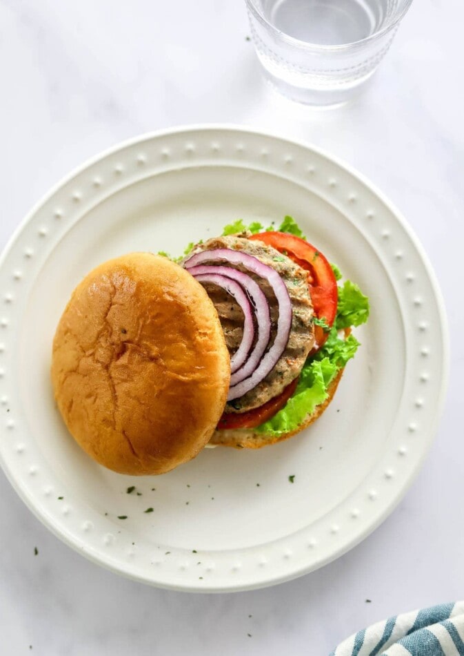 Overhead photo of a turkey burger topped with red onion, lettuce and tomato.