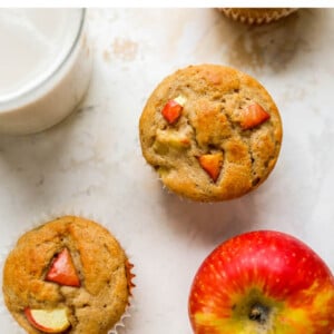 Overhead view of apple yogurt muffins scattered around with an apple.