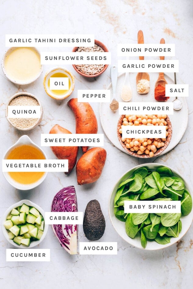 Ingredients measured out to make buddha bowls: garlic tahini dressing, sunflower seeds, onion powder, garlic powder, oil, pepper, salt, chili powder, quinoa, sweet potatoes, chickpeas, vegetable broth, baby spinach, cucumber, cabbage and avocado.