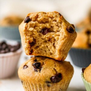 Two chocolate chip yogurt muffins stacked on top of each other. The top muffin has a bite taken out of it.