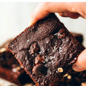 A hand holding up an oat flour brownie square.