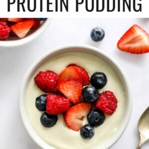 A small dish containing vanilla protein pudding topped with berries.