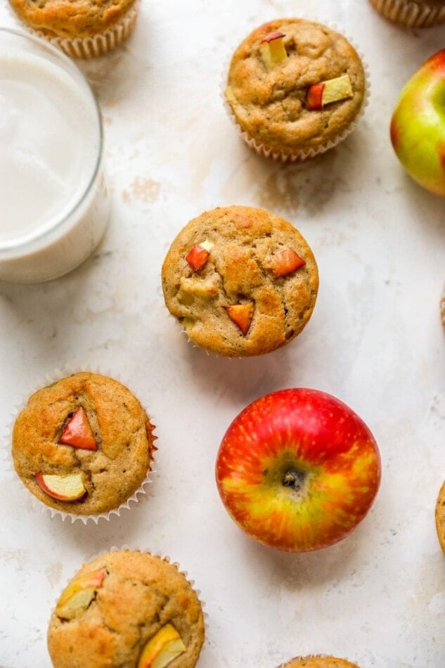 Overhead view of apple yogurt muffins scattered around with an apple.