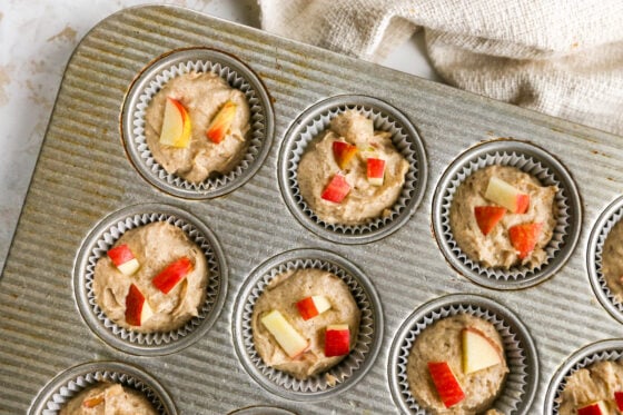 Apple yogurt muffin batter divided into muffin tin with paper liners.