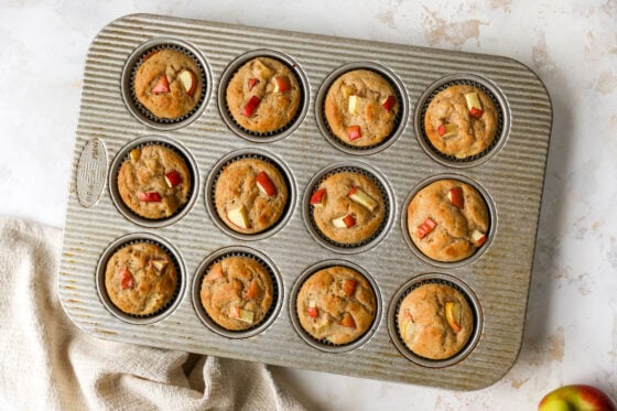 Twelve baked apple yogurt muffins in a muffin tin.