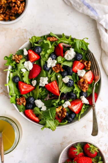 A bowl with summer berry salad. A fork rests on bowl.