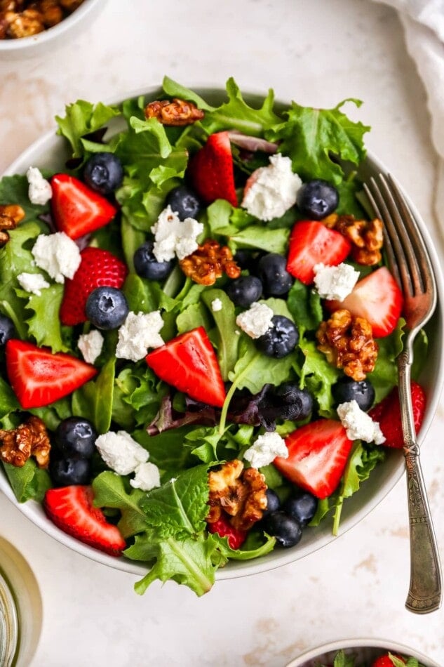Close up of summer berry salad in a bowl with a fork.