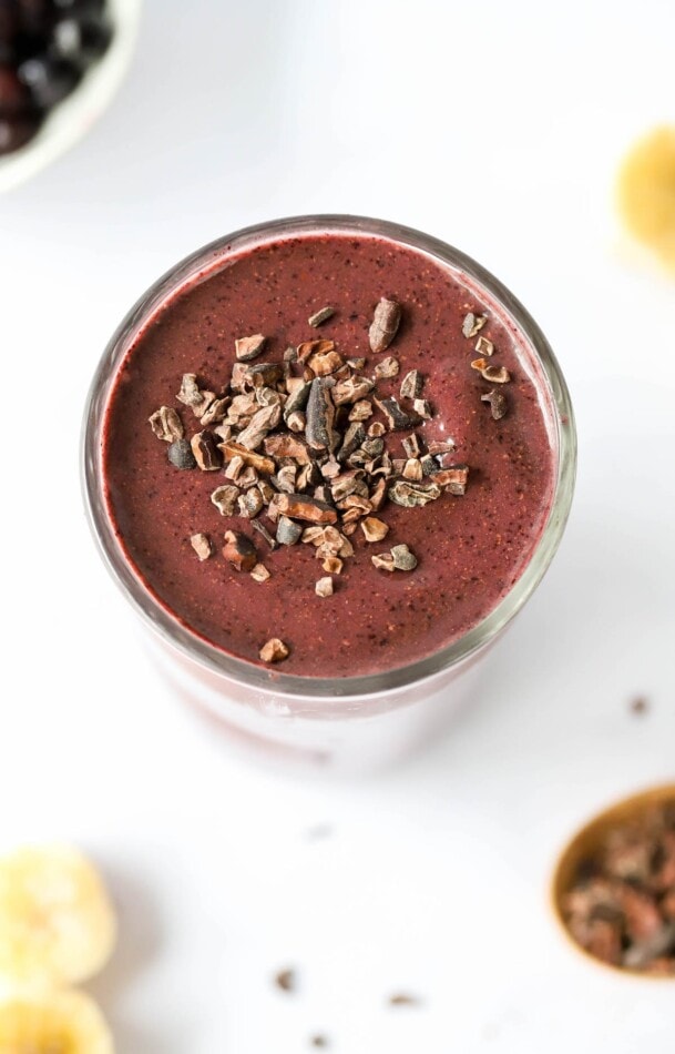 Overhead view of a cacao smoothie in a glass cup. It has been topped with cacao shavings.