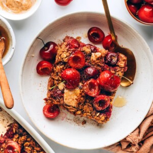 A serving of cherry baked oatmeal on a plate with a spoon.