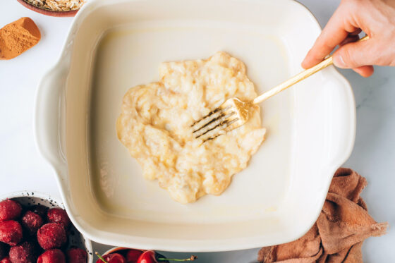 Mashing banana into the baking dish.