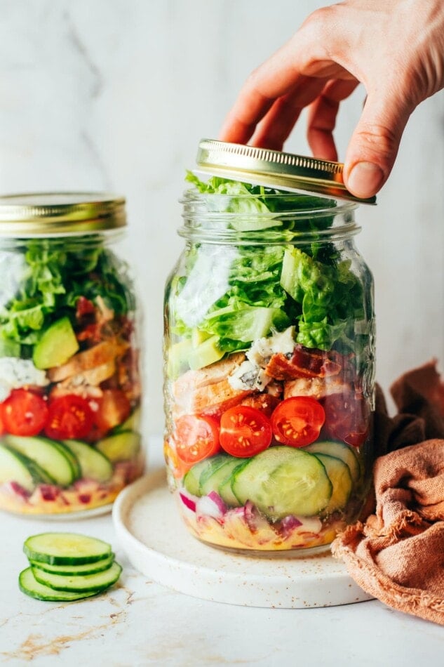 Two chicken avocado club salads in jars side by side.