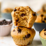 Two chocolate chip yogurt muffins stacked on top of each other. The top muffin has a bite taken out of it.