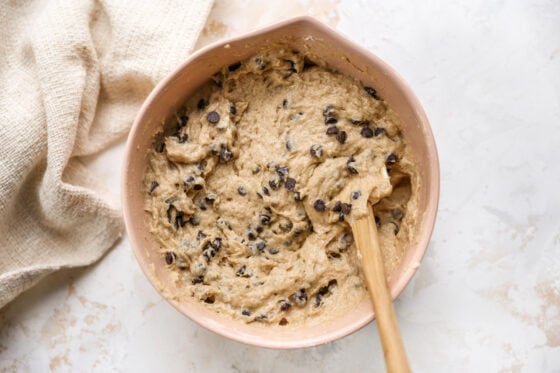 Chocolate chips mixed into muffin batter in a mixing bowl.
