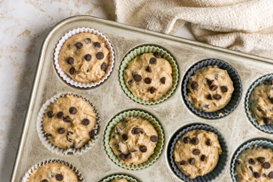 Chocolate chip yogurt muffin batter divided into a muffin tin lined with silicone liners.