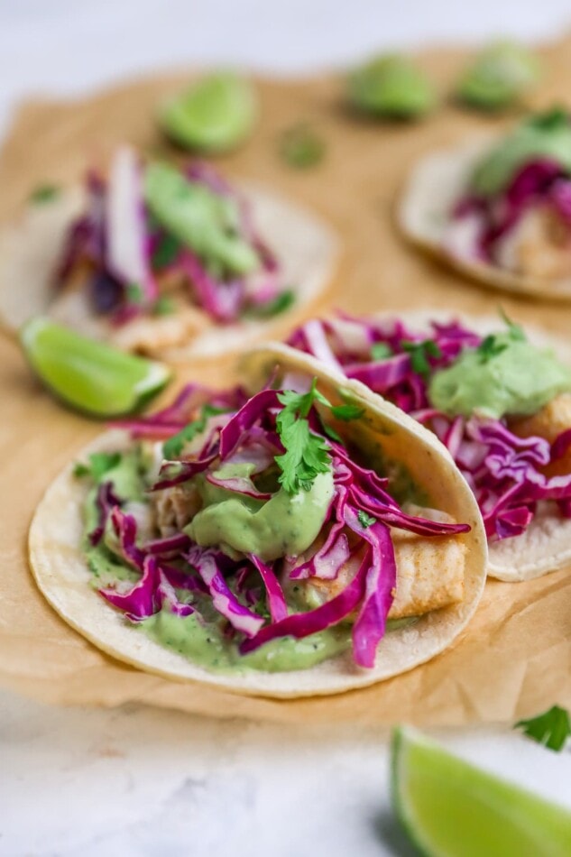 Fish tacos on sheet of parchment paper.