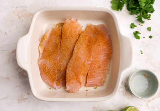 Seasoned white fish in a baking dish.