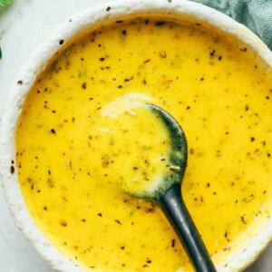 Nicoise salad dressing in a bowl with a spoon.