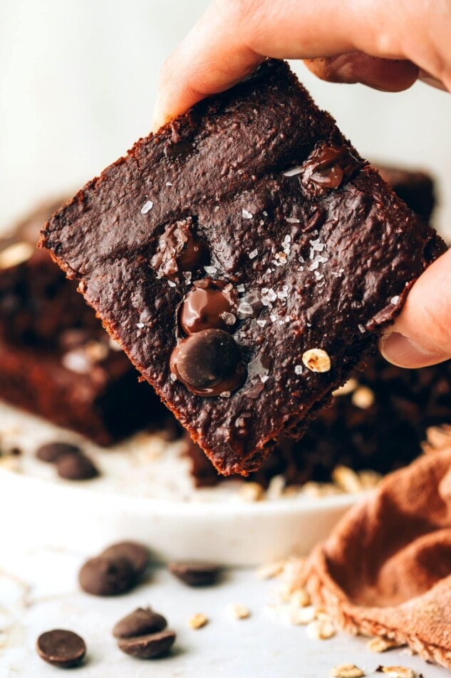 A hand holding up an oat flour brownie square.
