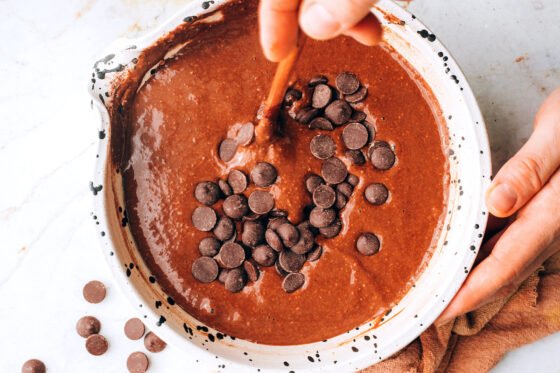 Mixing in chocolate chips to the brownie batter.