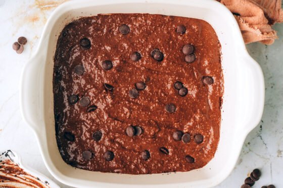 Spreading the brownie batter evenly throughout the prepared 8x8 pan.