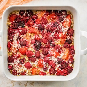 One pan baked oatmeal with berries and coconut flakes in a square baking dish.