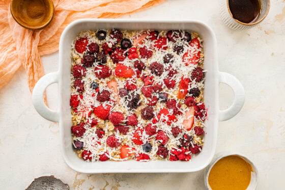 Shredded coconut sprinkled over top of berry oatmeal mixture in square baking dish.