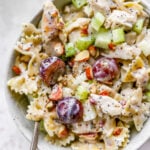 A bowl of poppyseed chicken pasta salad. A spoon rests in the bowl.