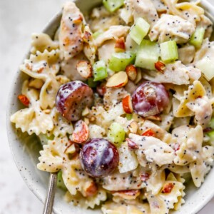 A bowl of poppyseed chicken pasta salad. A spoon rests in the bowl.