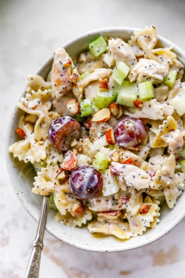 A bowl of poppyseed chicken pasta salad. A spoon rests in the bowl.