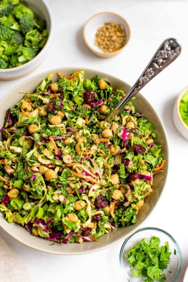 A bowl, left of center, containing sunflower crunch salad. It's surrounded by smaller bowls containing salad ingredients.