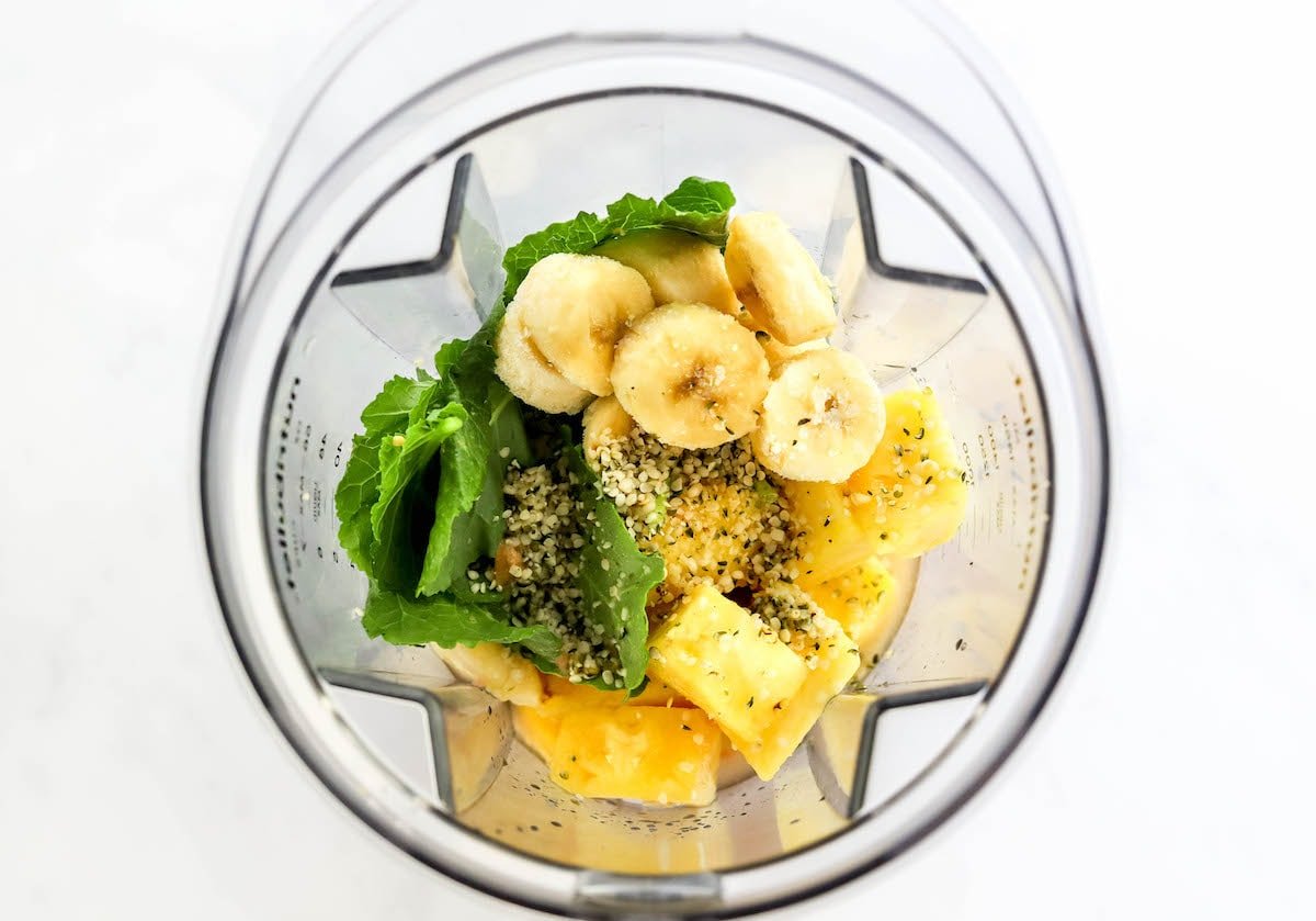Frozen banana slices, pineapple, kale and hemp seeds and grapefruit juice in a blender.